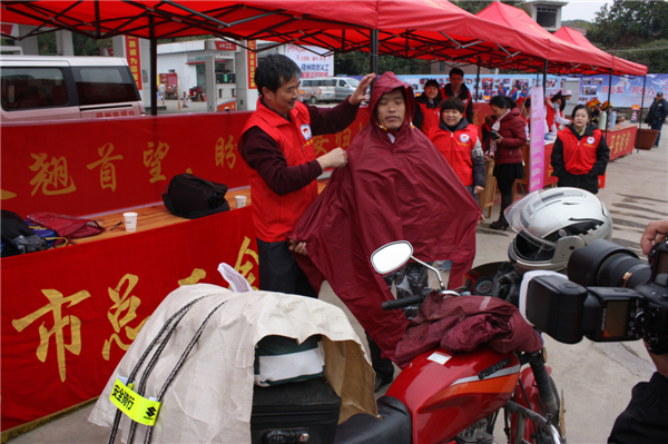 梧州市總工會的黨員義工們在市東出口春運服務(wù)站助力&ldquo;摩托大軍&rdquo;平安返鄉(xiāng)，幫助他們檢查車輛和行李，穿上雨衣。--黃賀峰攝.j